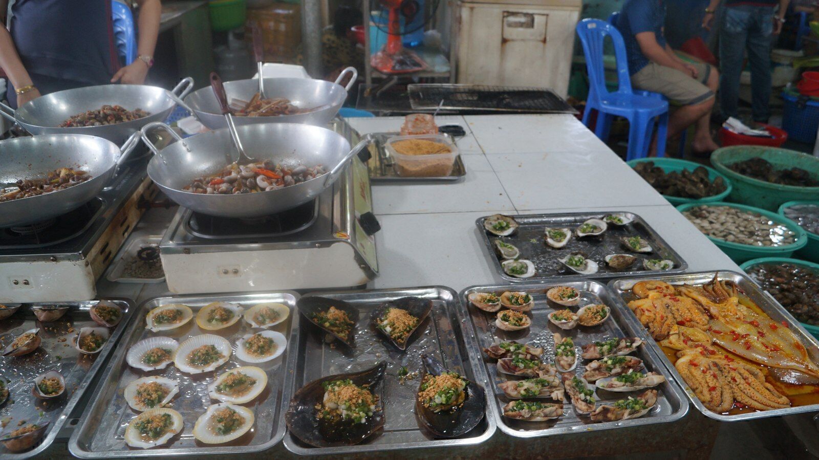 Trays of grilled shellfish and woks of cooked seafood at Hang Duong market in Can Gio