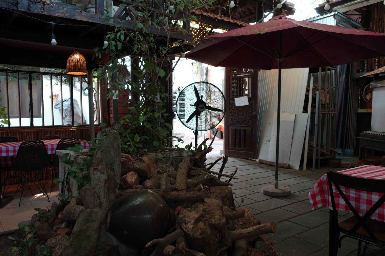 Quiet garden courtyard cafe with red umbrella and checked tablecloths in Da Nang