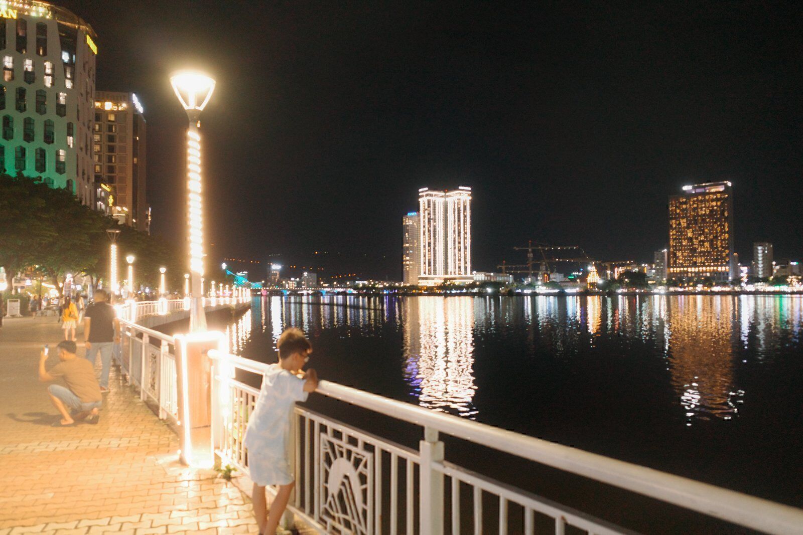 Han River promenade in Da Nang at night with ornate lamp posts and the lit east-bank skyline across the water