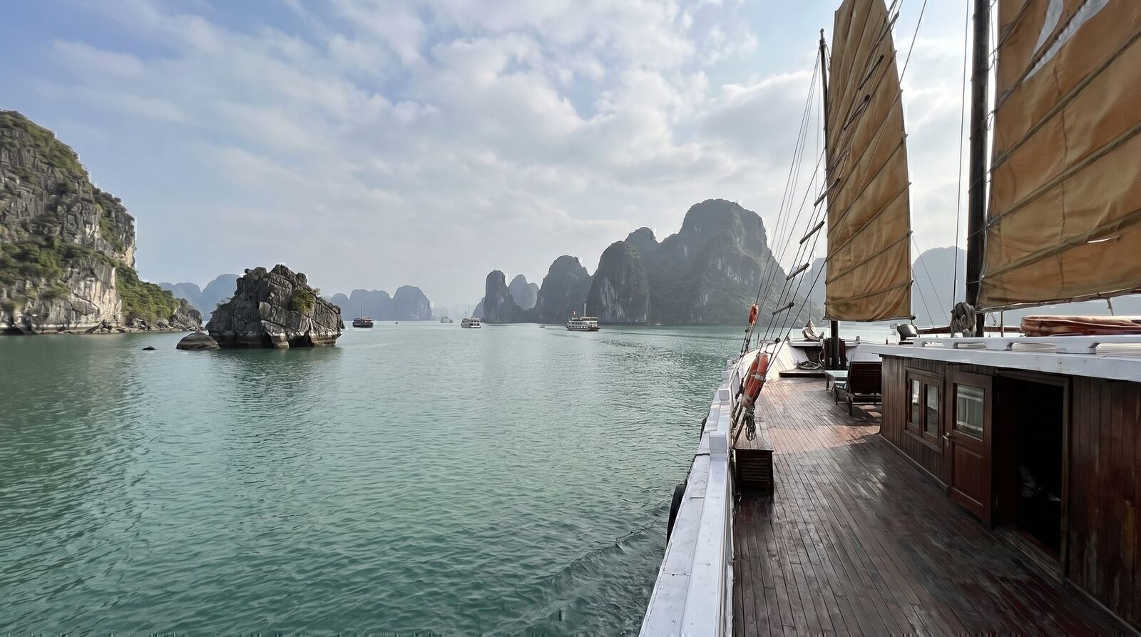 View from the deck of a traditional cruise boat over clear Ha Long Bay karsts on a November day