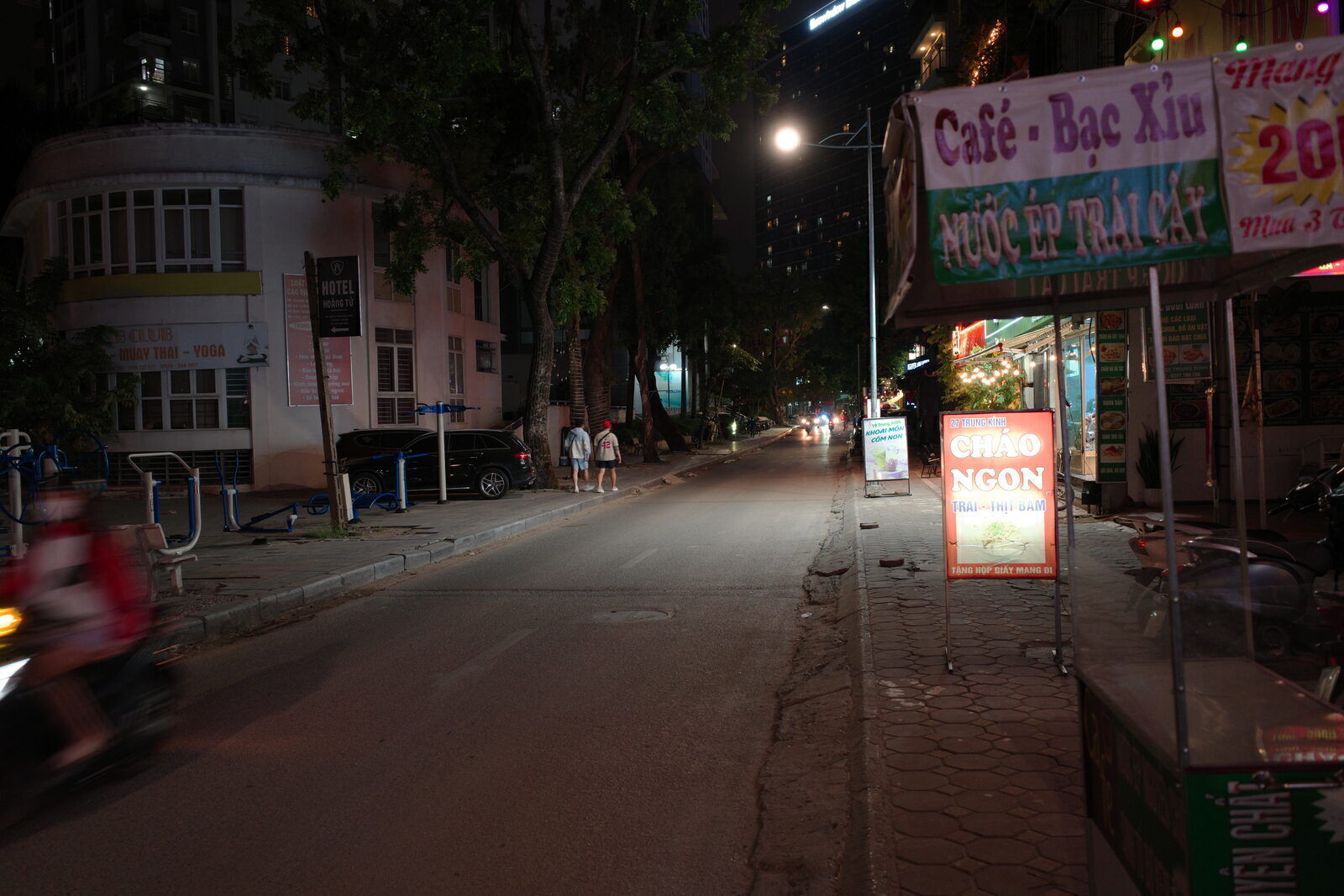 Quiet Hanoi street at night with glowing Vietnamese food and coffee signs on Trung Kinh street