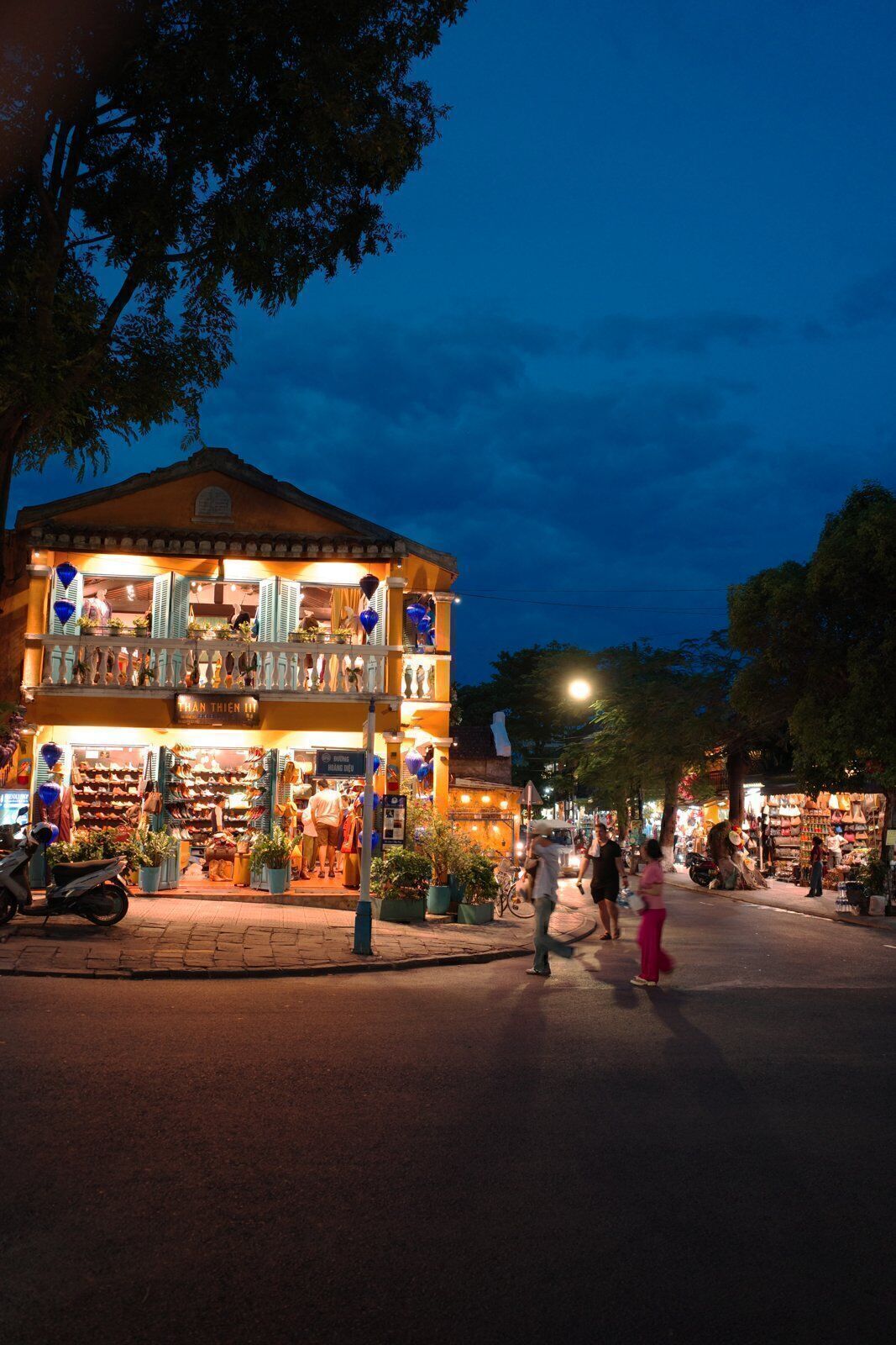 Lantern shop glowing at dusk on a Hoi An street with evening sky