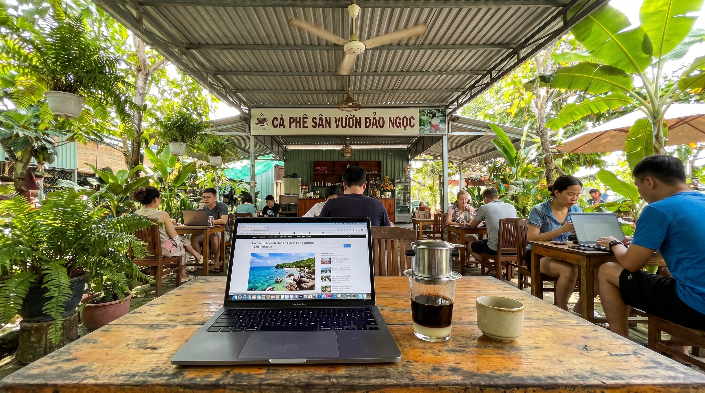 Laptop and Vietnamese phin coffee at an open-air tropical cafe workspace in Phu Quoc