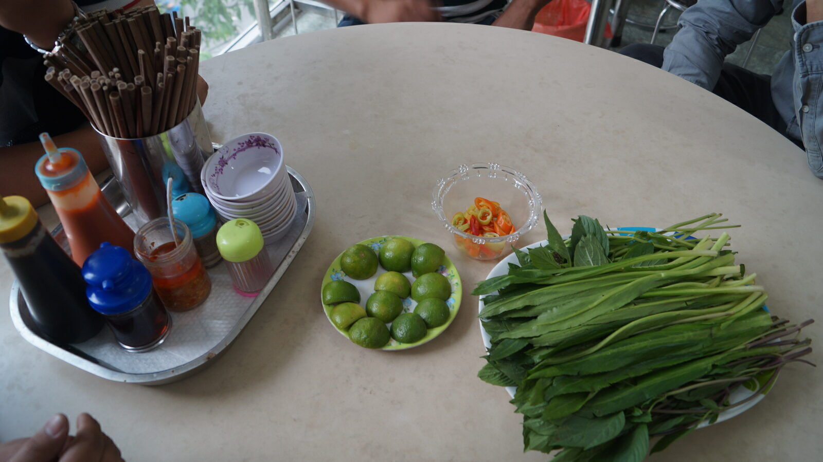 Vietnamese street restaurant table with limes, chilies, fresh herbs and condiment tray in Saigon