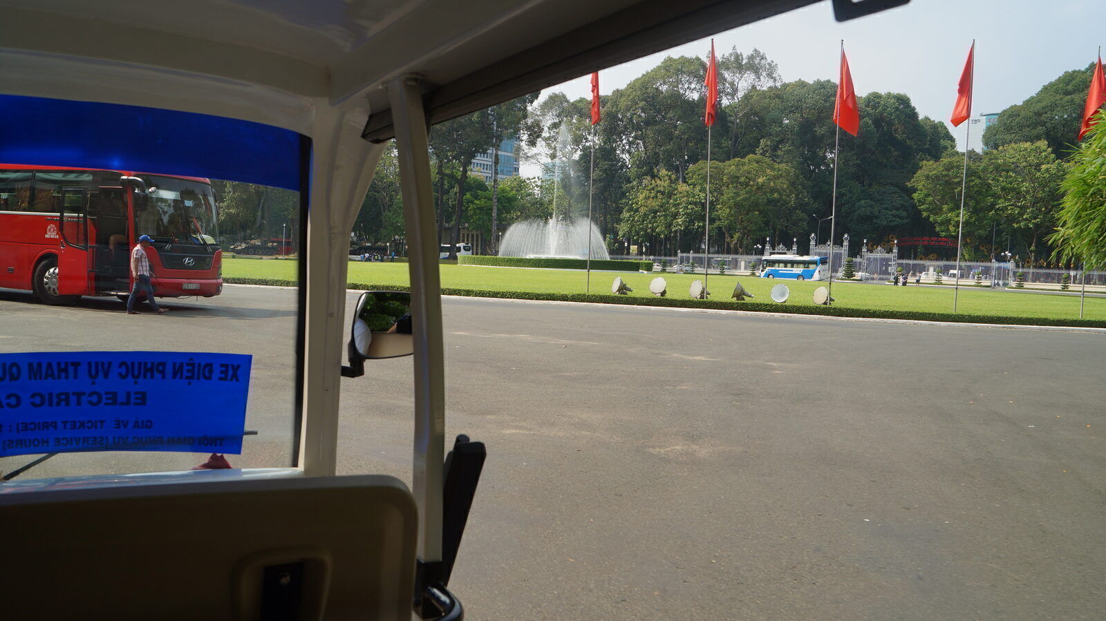 Independence Palace grounds in Saigon seen from an electric visitor cart with red flags and fountain