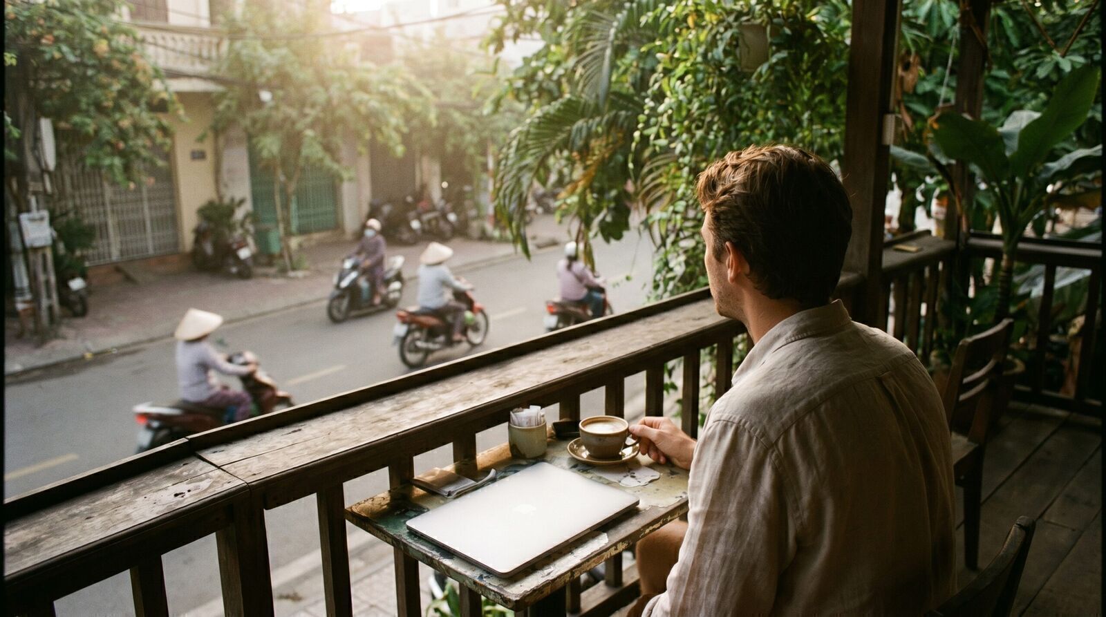 Traveler having morning coffee on a balcony overlooking a quiet Vietnamese street