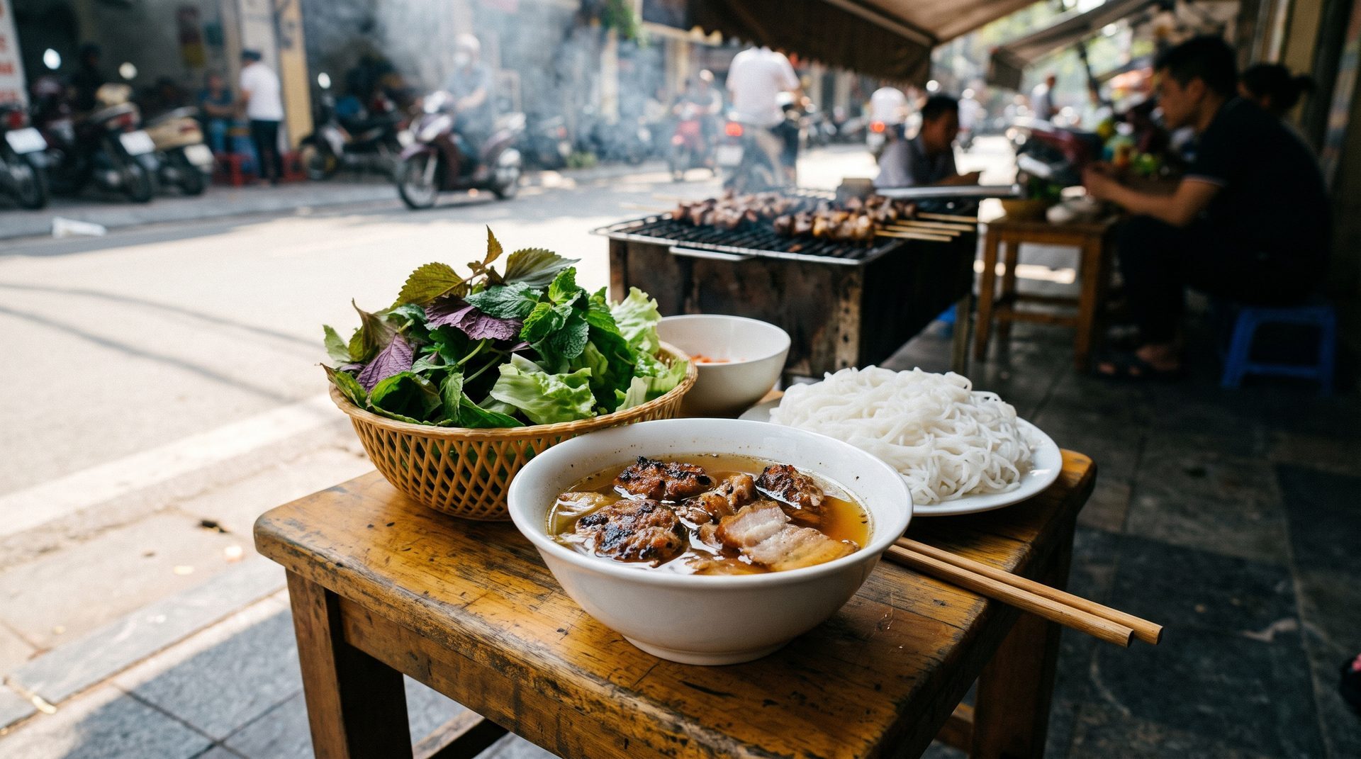 Bun cha lunch in Hanoi - charcoal grilled pork patties in dipping broth with fresh herbs and rice noodles on a low table