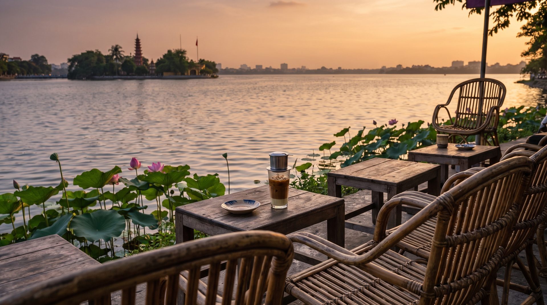 Quiet lakeside cafe terrace on West Lake in Hanoi at golden hour with rattan chairs and a view across the water