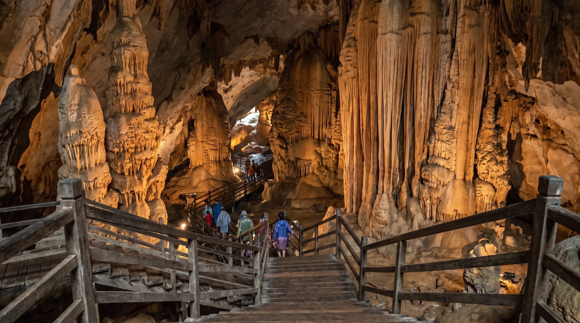 Wooden boardwalk descending into the vast lit chamber of Paradise Cave in Phong Nha with building-sized stalagmites