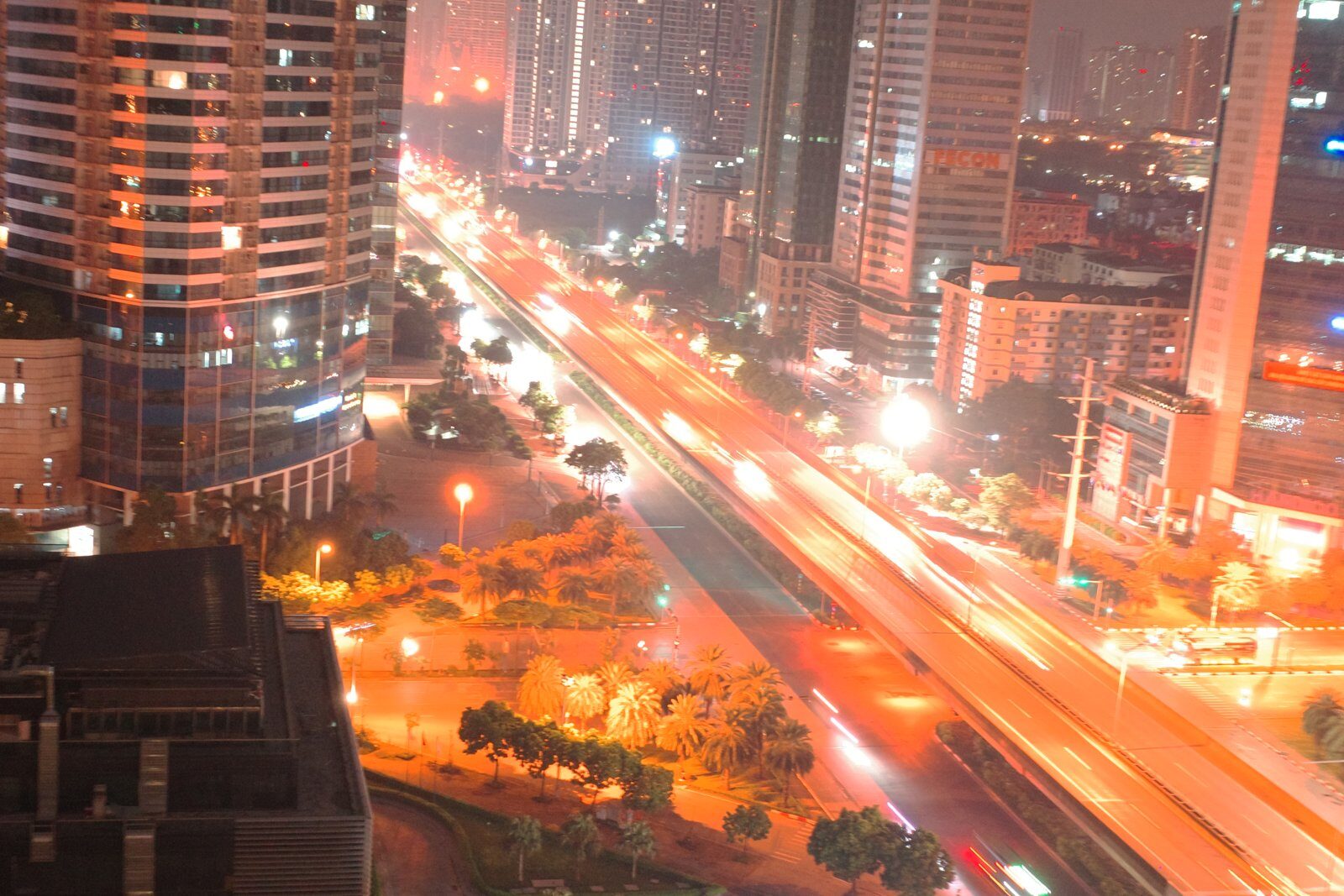 Night view over western Hanoi from a high apartment window: towers, light trails and an empty boulevard