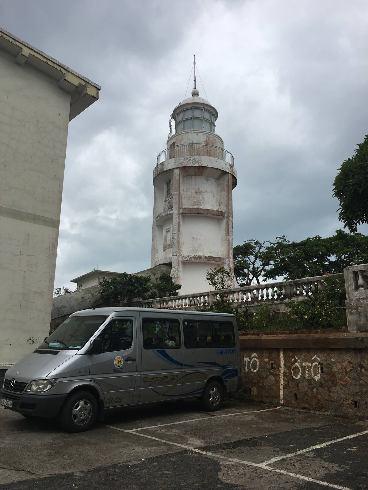 The white colonial-era Vung Tau lighthouse on Nui Nho hill under monsoon clouds