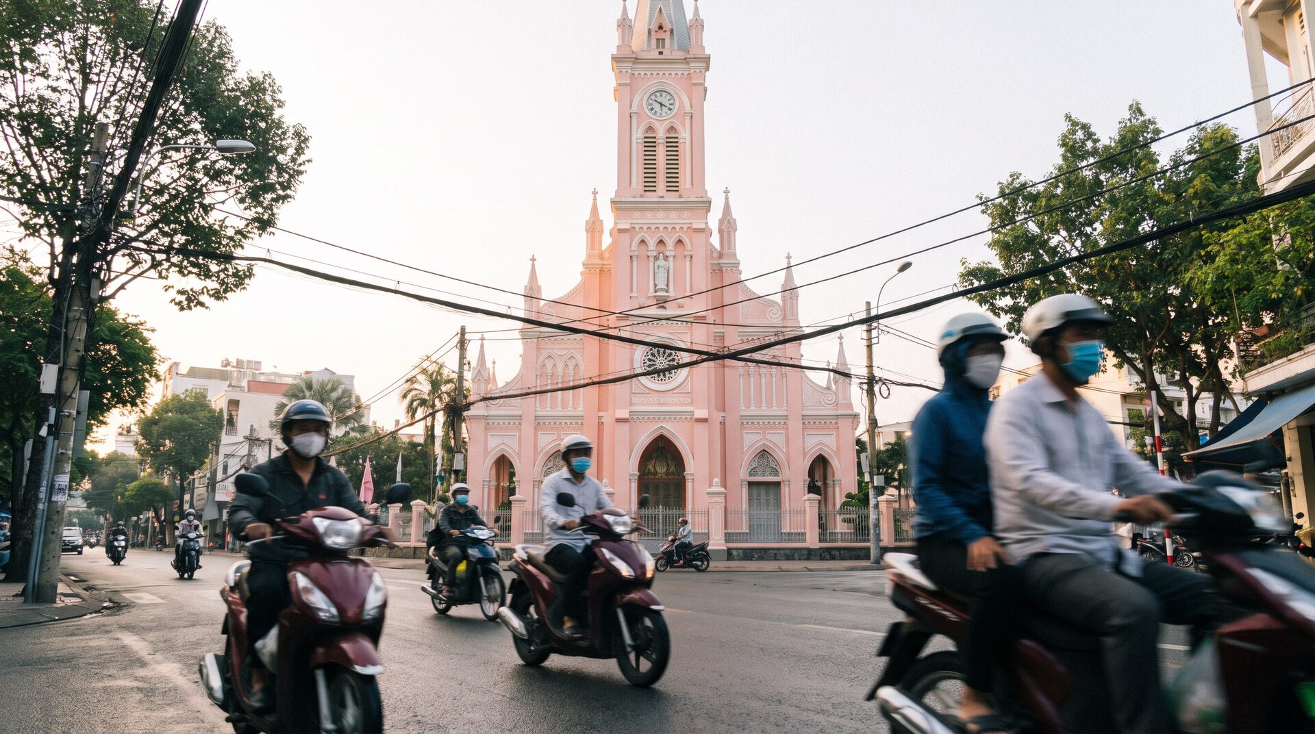 The pastel pink facade of Tan Dinh Church in Saigon with morning motorbike traffic streaming past