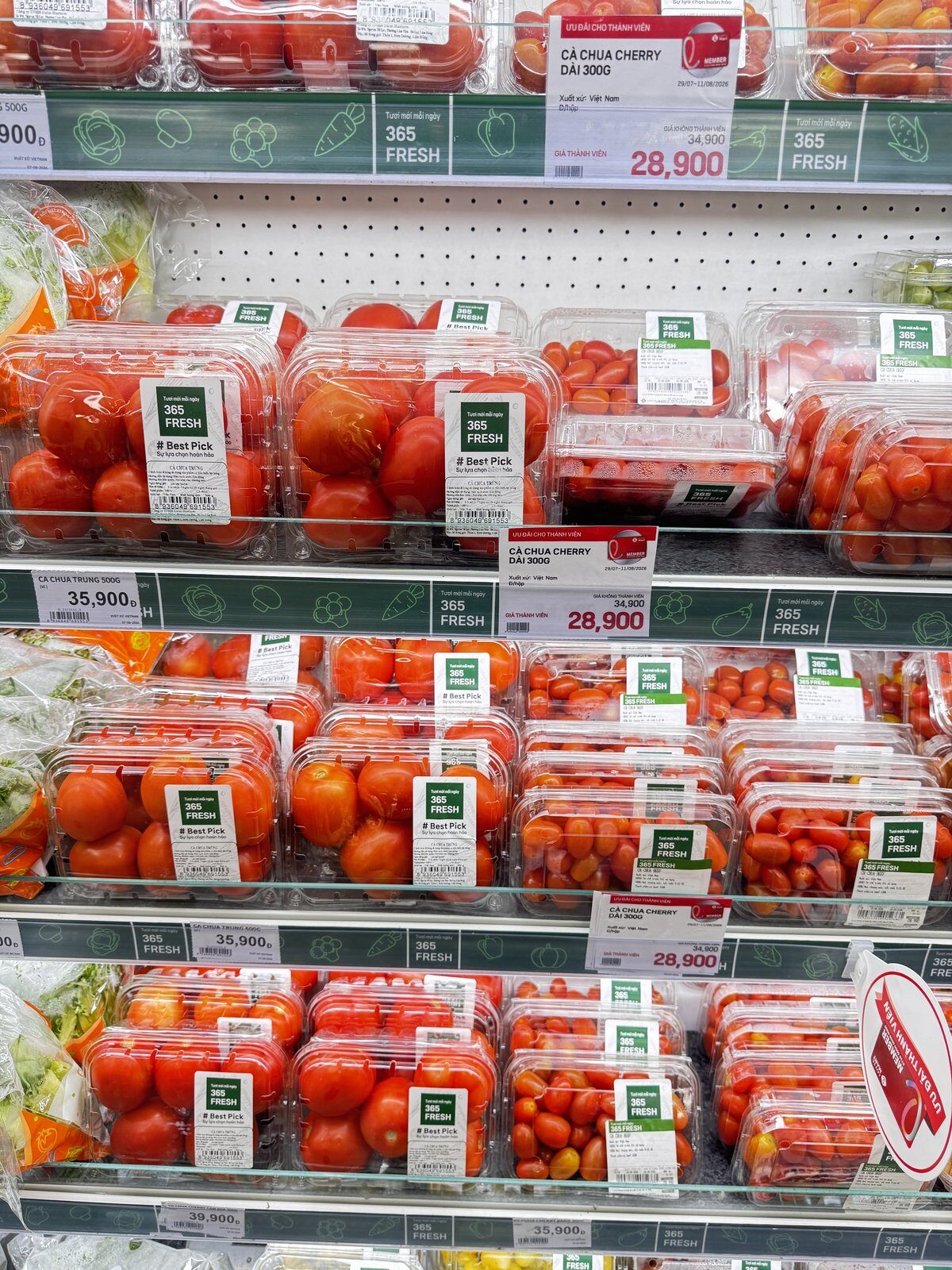 Supermarket shelf in Hanoi with packs of cherry tomatoes and printed price tags reading 28,900 dong